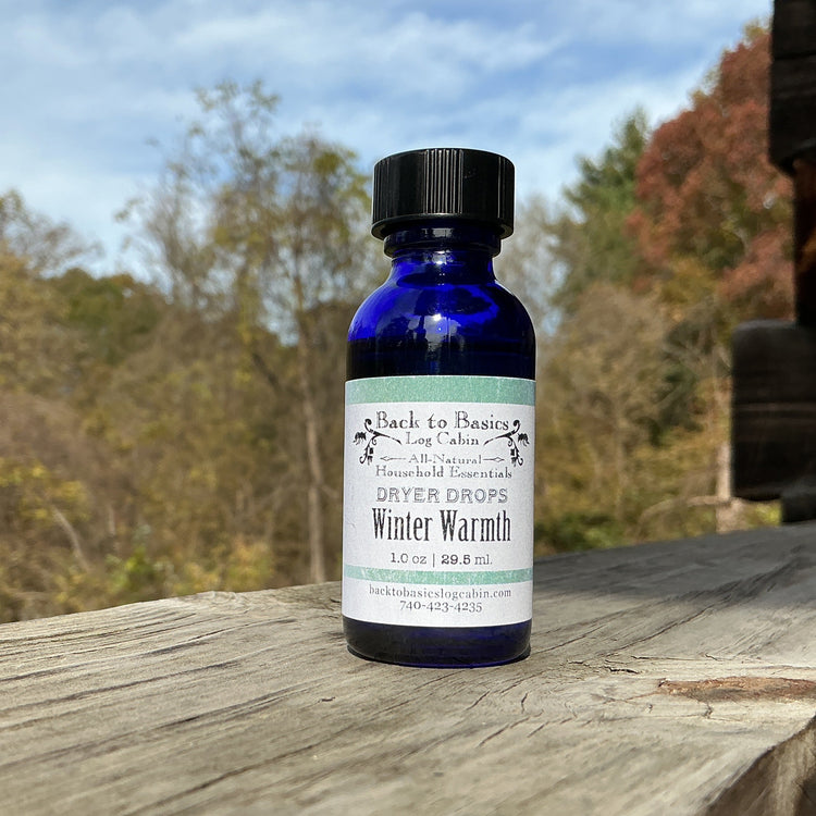 Blue bottle labeled 'Winter Warmth' on a wooden surface with a natural background