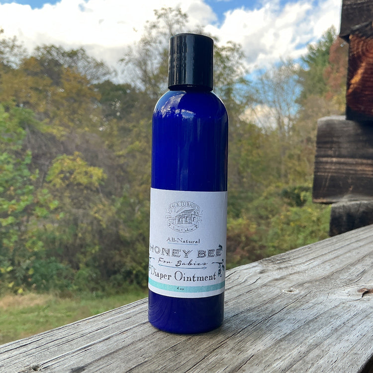 Blue bottle of 'Honey Bee' ointment on a wooden surface with a natural background