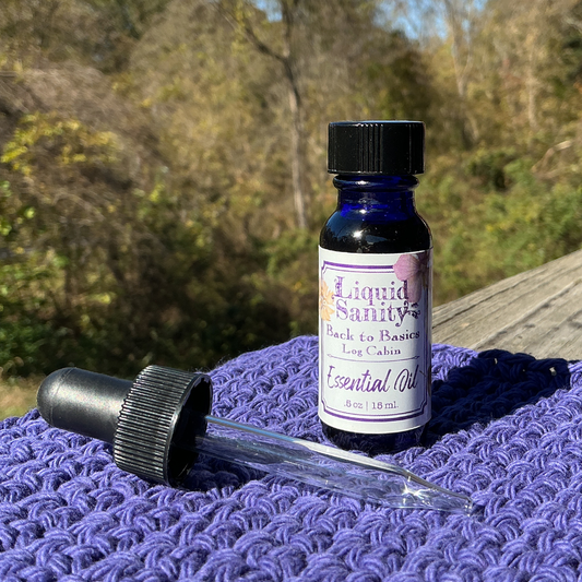 Bottle of 'Liquid Sanity' essential oil with dropper on a purple textured surface outdoors.