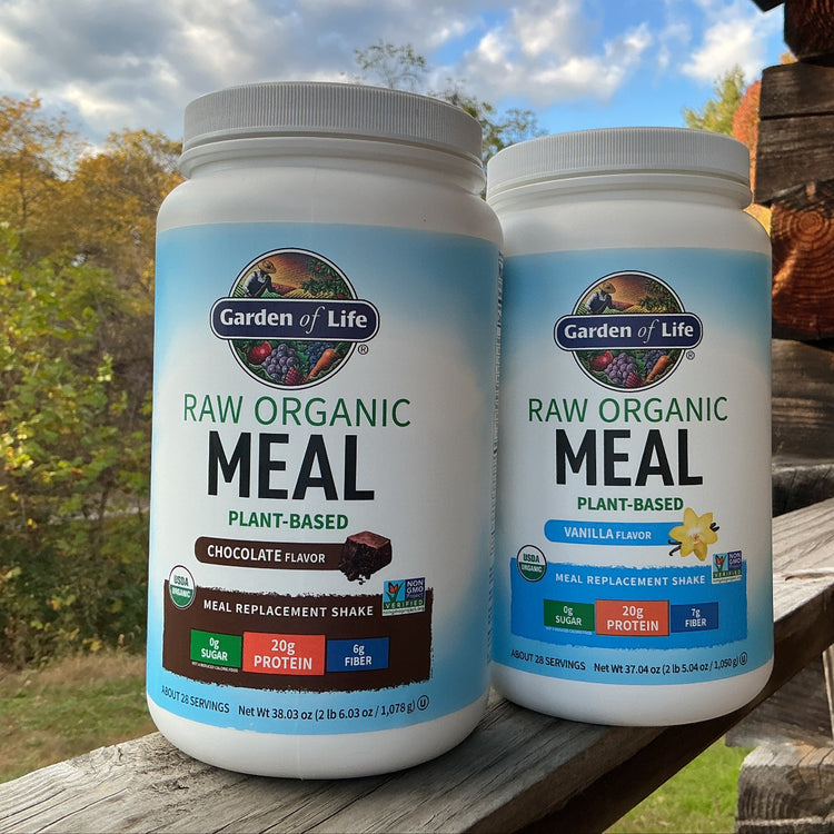Two Garden of Life raw organic meal plant-based containers on a wooden surface with a natural background.