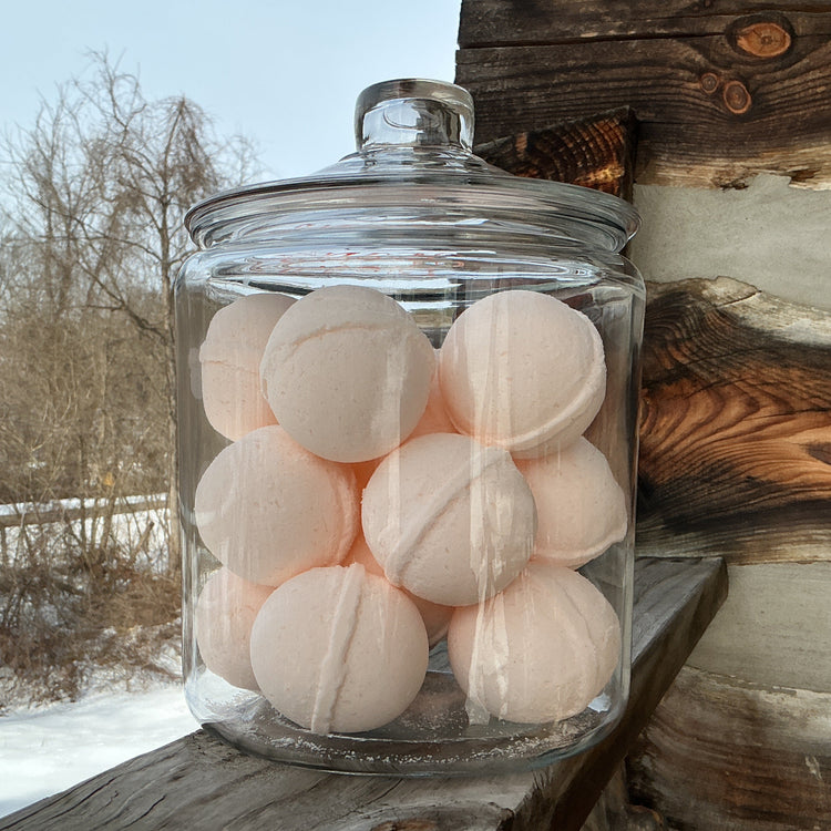 Glass jar filled with white bath bombs on a wooden surface outdoors.