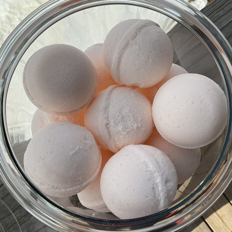 Clear glass bowl filled with white bath bombs on a wooden surface.