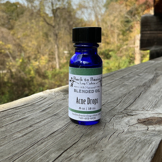 Bottle of 'Acne Drops' blended oil on a wooden surface with a natural background