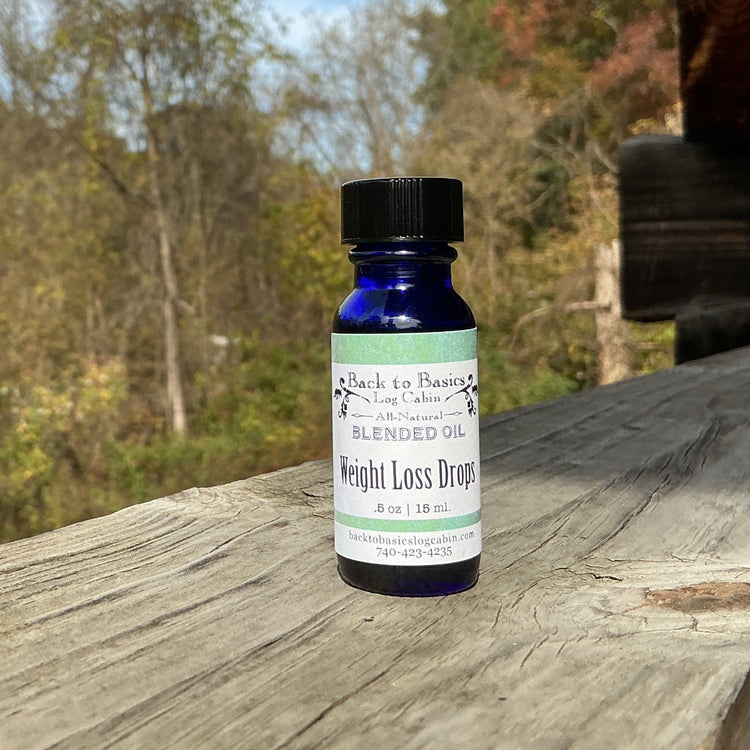 Blue bottle labeled 'Weight Loss Drops' on a wooden surface with a natural background
