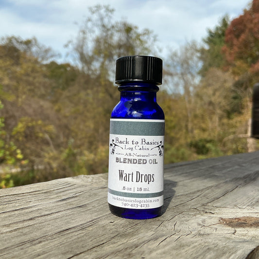 Blue bottle labeled 'Wart Drops' on a wooden surface with a natural background