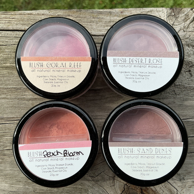 Four makeup products in black containers on a wooden surface