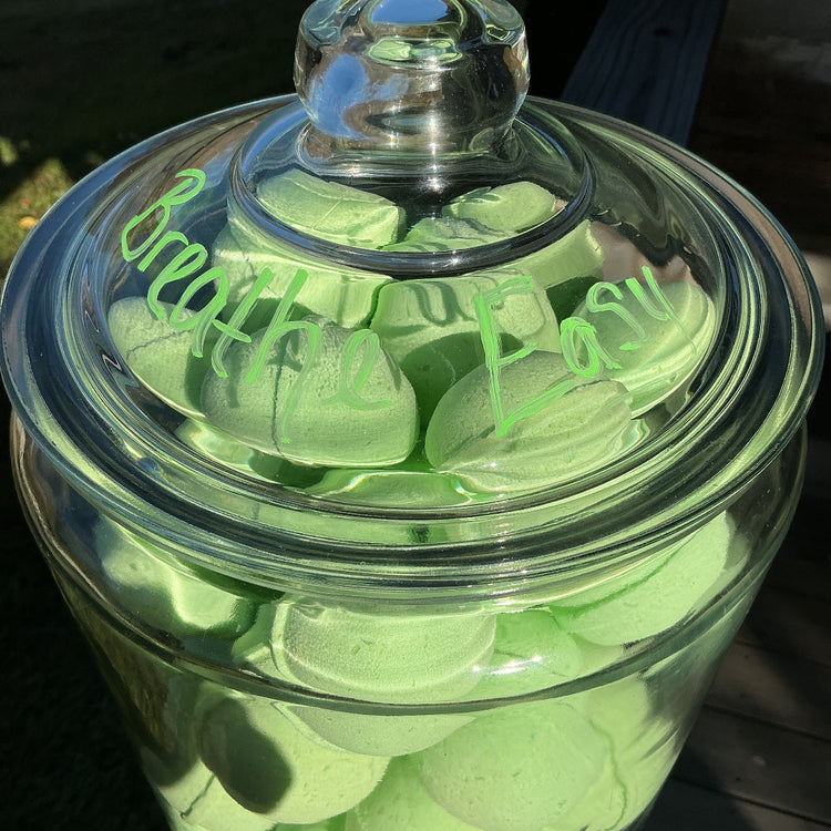 Clear glass jar filled with green heart-shaped objects on a dark background