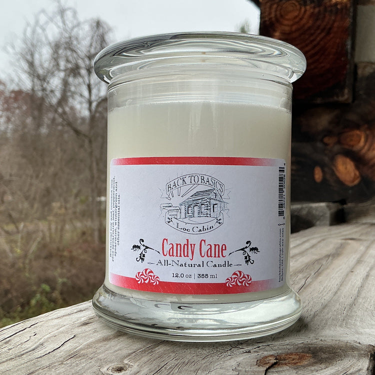 Candle in a glass jar with a label on a wooden surface outdoors