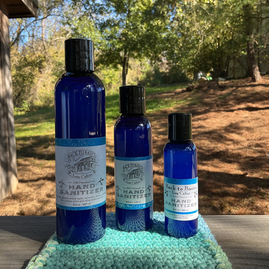 Three bottles of hand sanitizer on a green towel outdoors with trees in the background