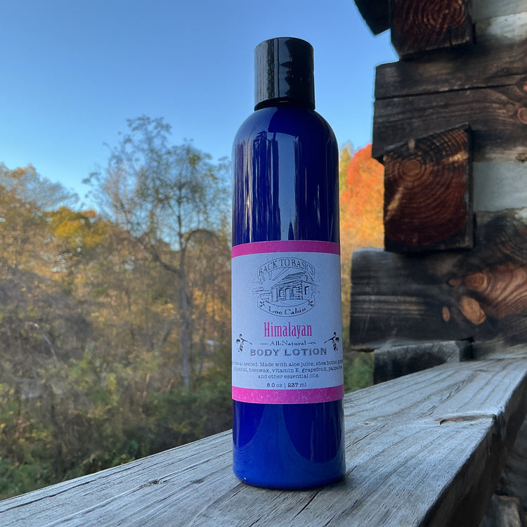 Blue bottle of Himalayan body lotion on a wooden surface with a scenic background