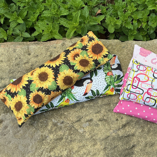 Three fabric bags with different patterns on a stone surface with greenery in the background