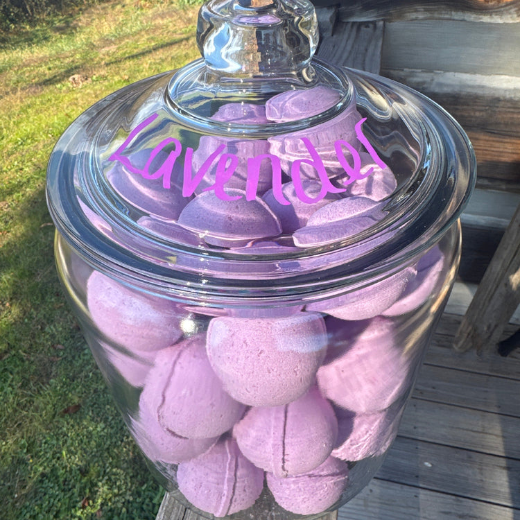 Clear glass jar filled with pink bath bombs on a wooden surface.