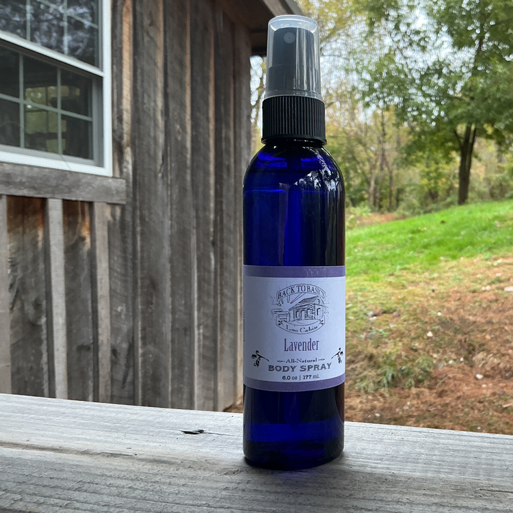 Blue spray bottle with lavender body spray on a wooden surface outdoors