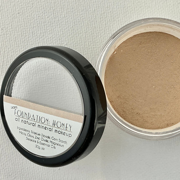 Open container of foundation powder with visible label on a light gray background