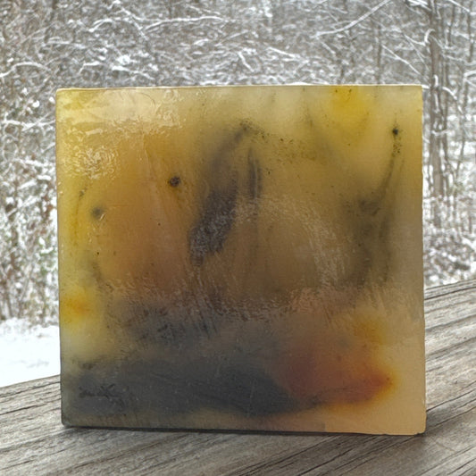 Rectangular bar of soap with a natural, multicolored pattern on a textured surface.