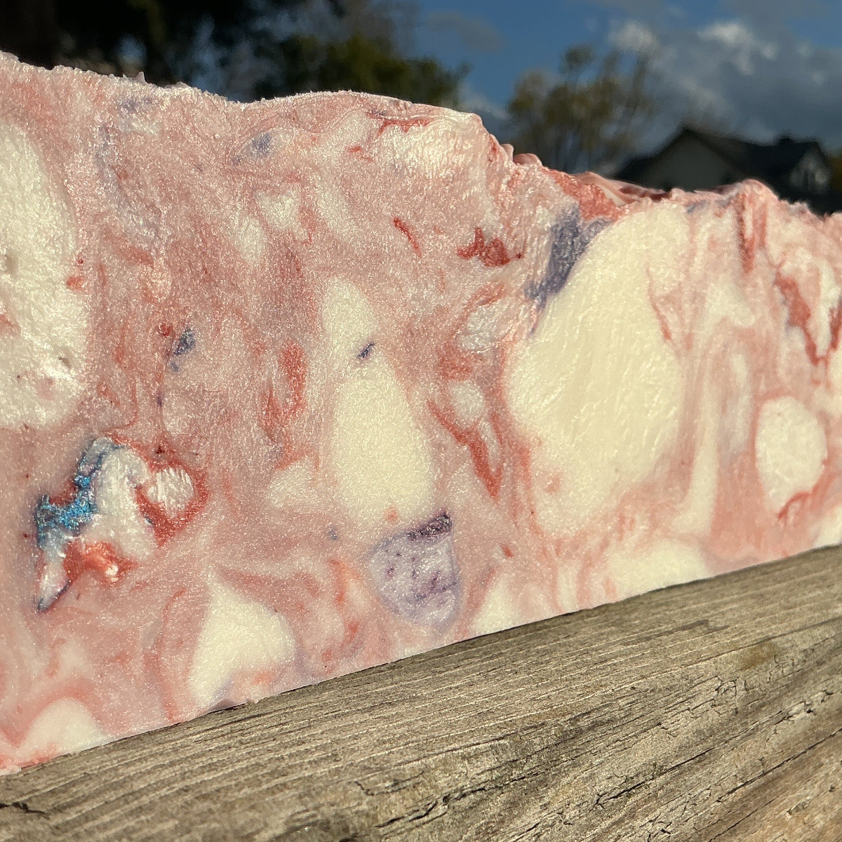 Marble-patterned soap bar on a wooden surface with a blurred natural background
