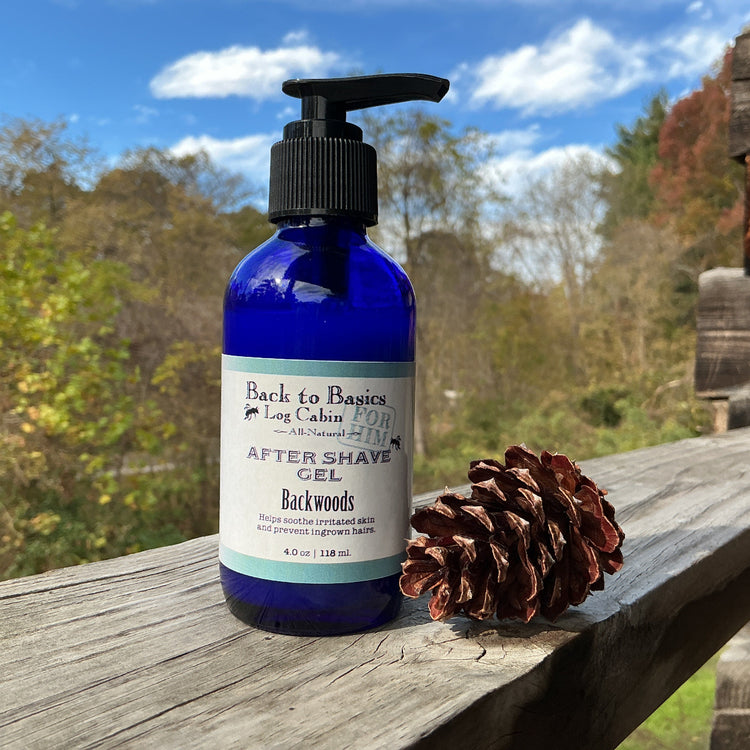 Blue bottle of 'Back to Basics' after-shave gel on a wooden surface with a pine cone and outdoor background.