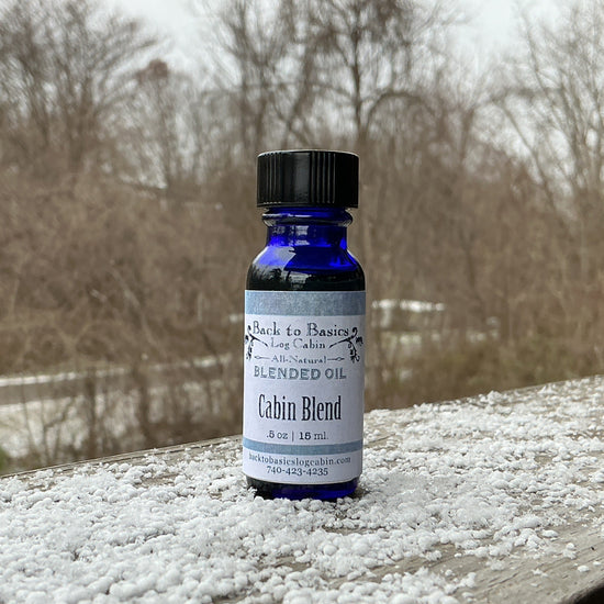 Bottle of 'Cabin Blend' oil on a wooden surface with snowflakes