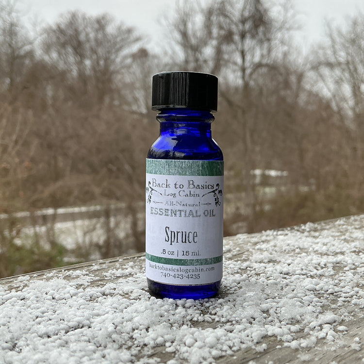 Bottle of essential oil labeled 'Spruce' on a wooden surface with snowflakes.