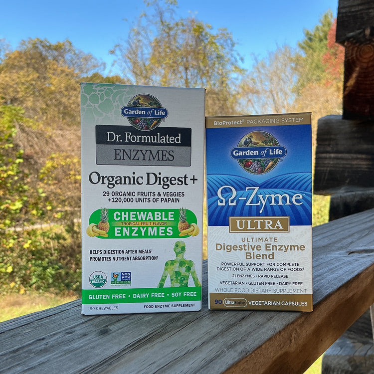 Two boxes of Garden of Life digestive enzyme products on a wooden surface with a natural background.