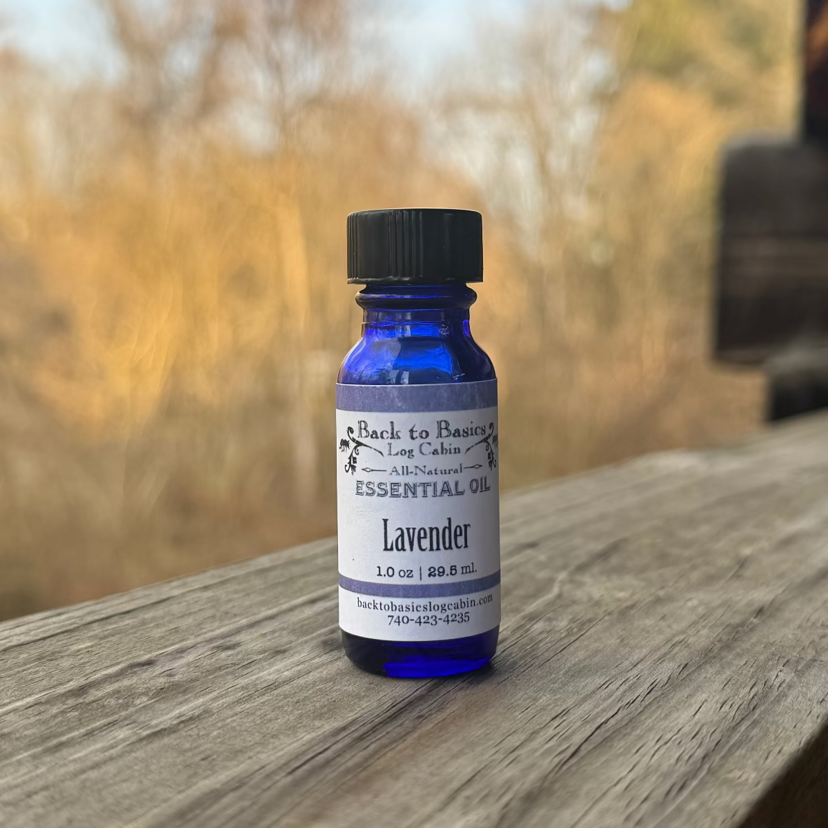 Bottle of lavender essential oil on a wooden surface with a blurred natural background