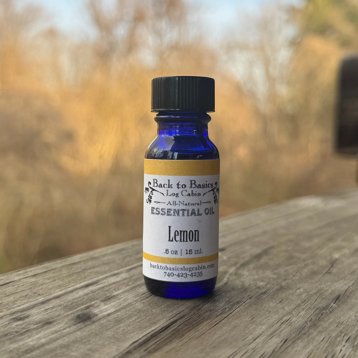 Bottle of lemon essential oil on a wooden surface with a blurred natural background