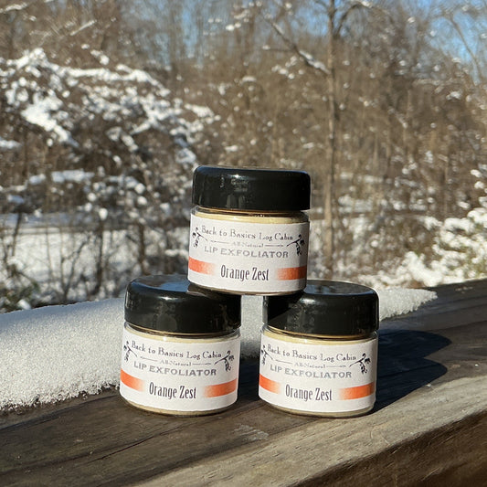 Four small jars with black lids on a wooden surface with a snowy landscape in the background.