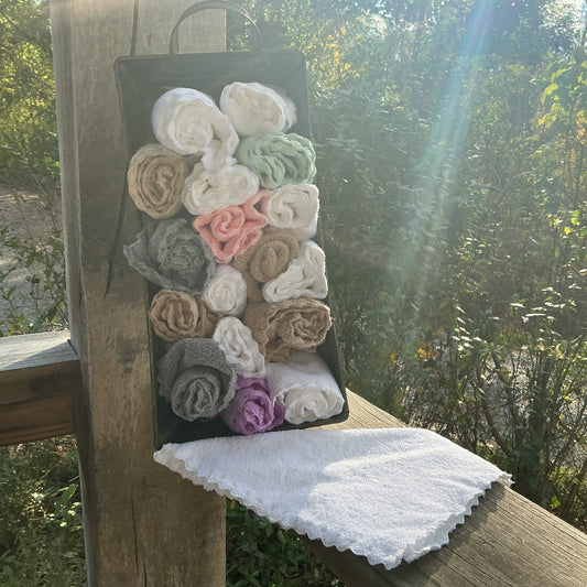 Set of rolled-up towels in a black holder on a wooden surface with a natural background