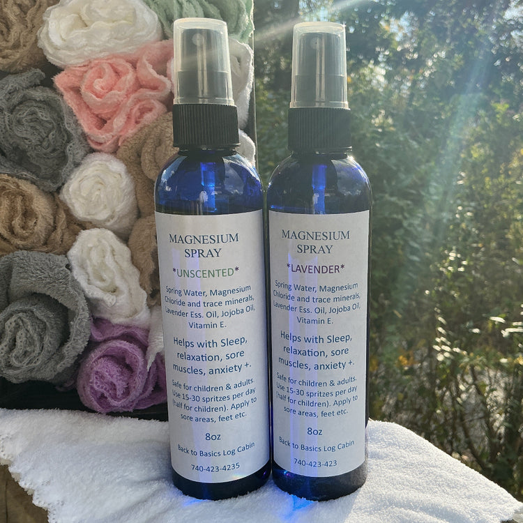 Two bottles of magnesium spray with labels on a textured surface outdoors.