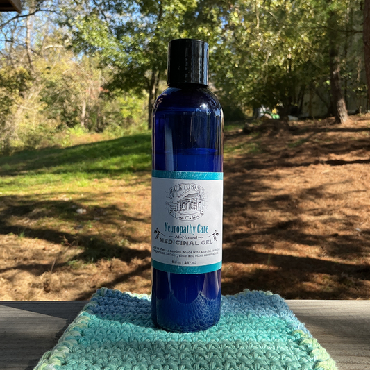 Blue bottle of medicinal gel on a green towel outdoors with trees in the background