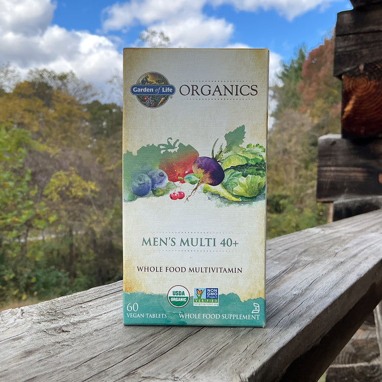 Box of Garden of Life Organics Men's Multi 40+ supplement on a wooden surface with a natural background.