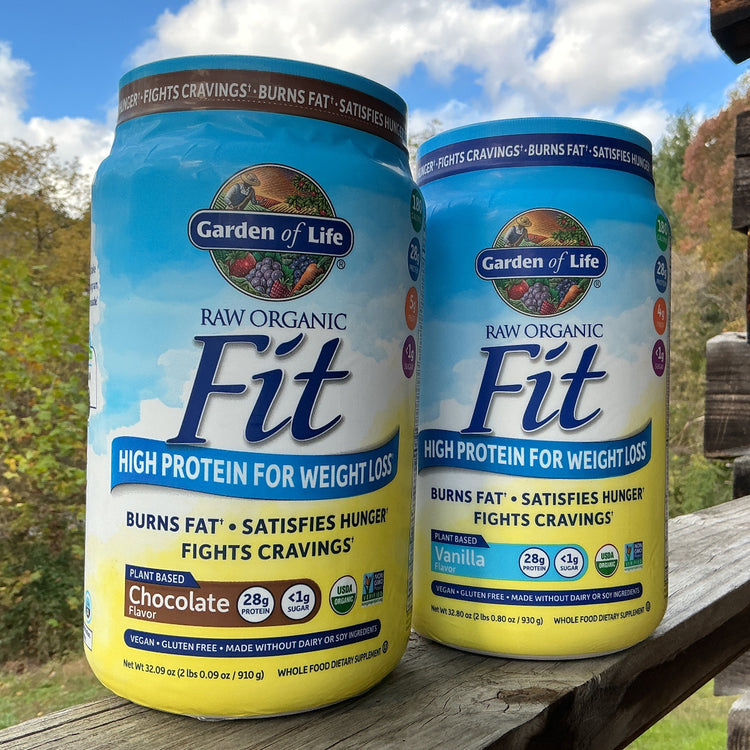 Two bottles of Garden of Life Raw Organic Fit High Protein for Weight Loss on a wooden surface with a natural background.