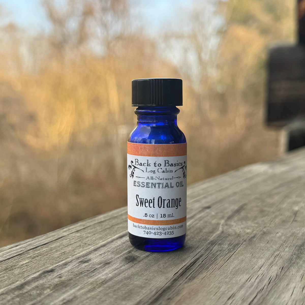 Bottle of sweet orange essential oil on a wooden surface with a blurred natural background