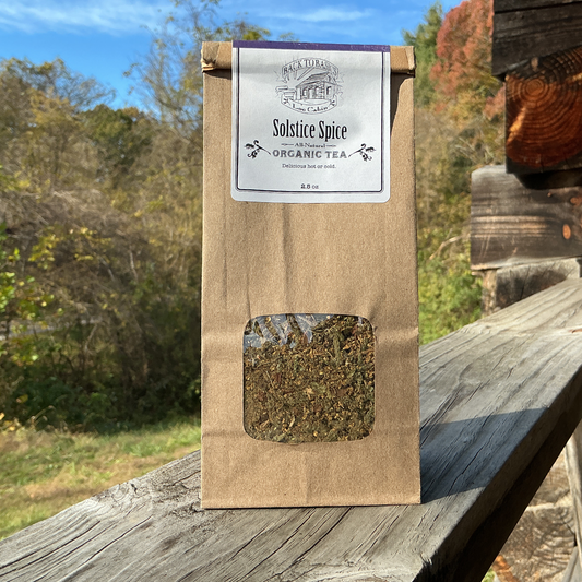 Tea package labeled 'Solstice Spice' on a wooden surface with a natural background