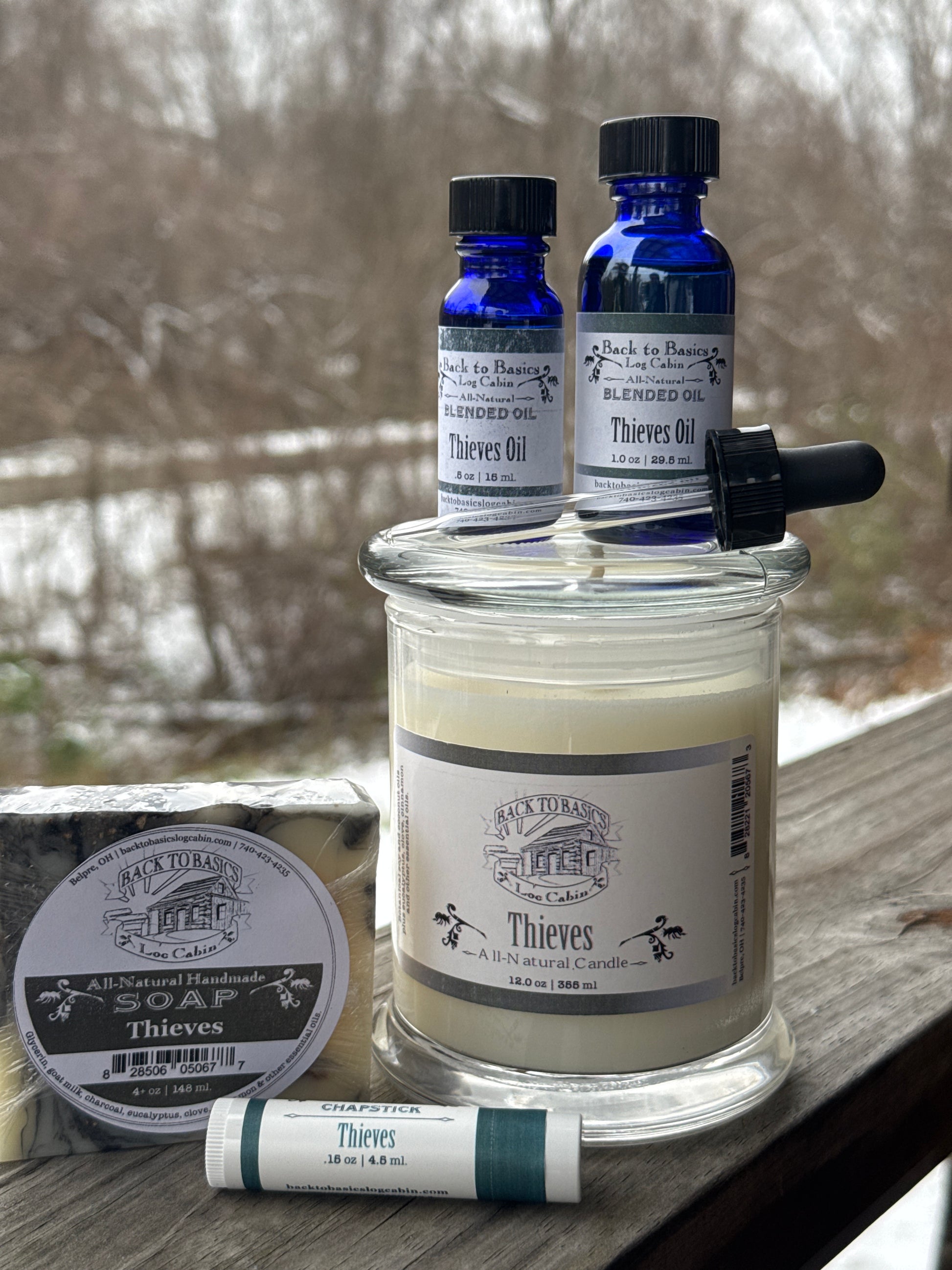 Collection of Thymes products including a large bottle, small bottles, and a bar of soap on a textured surface.