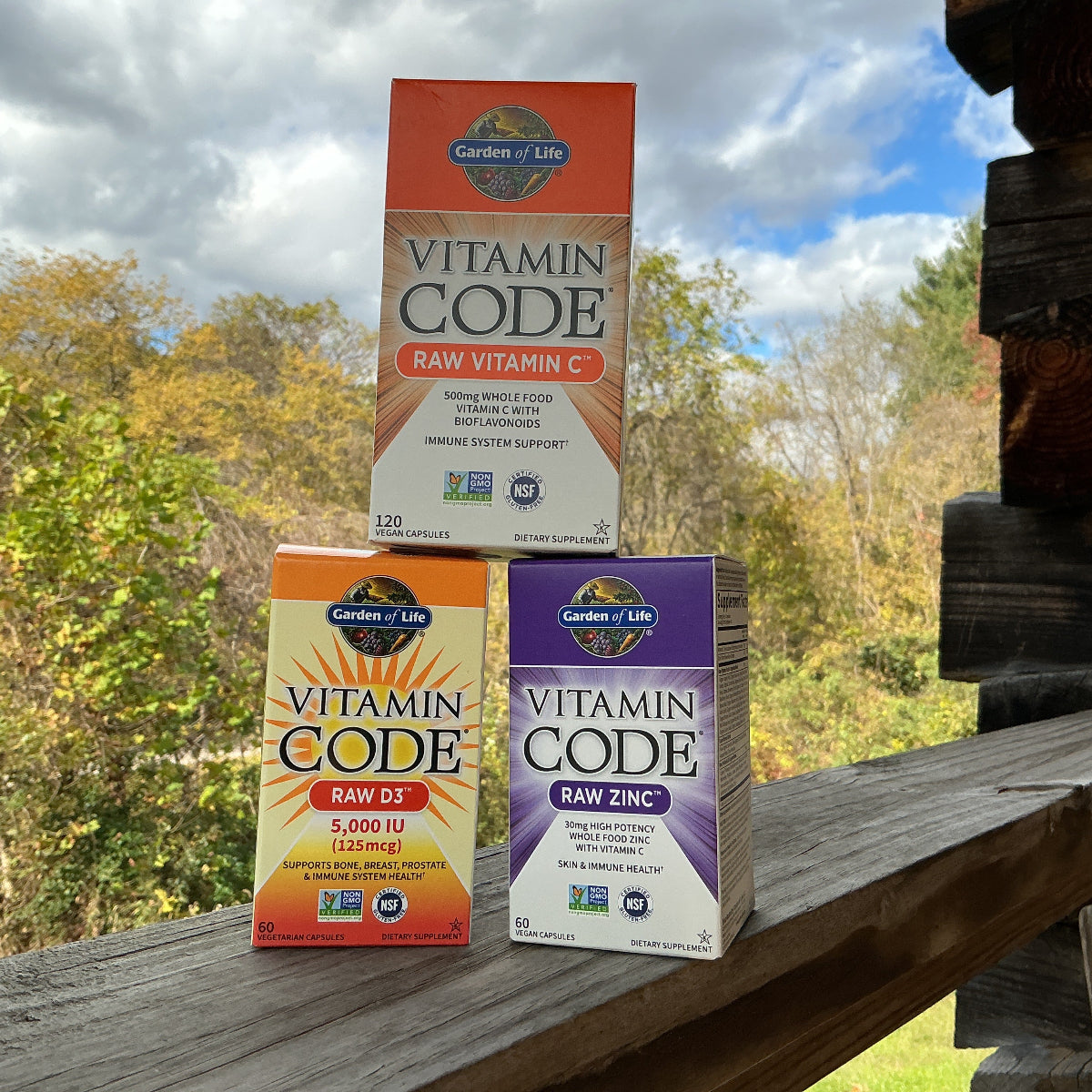 Three boxes of Garden of Life Vitamin Code supplements on a wooden surface with a natural background.
