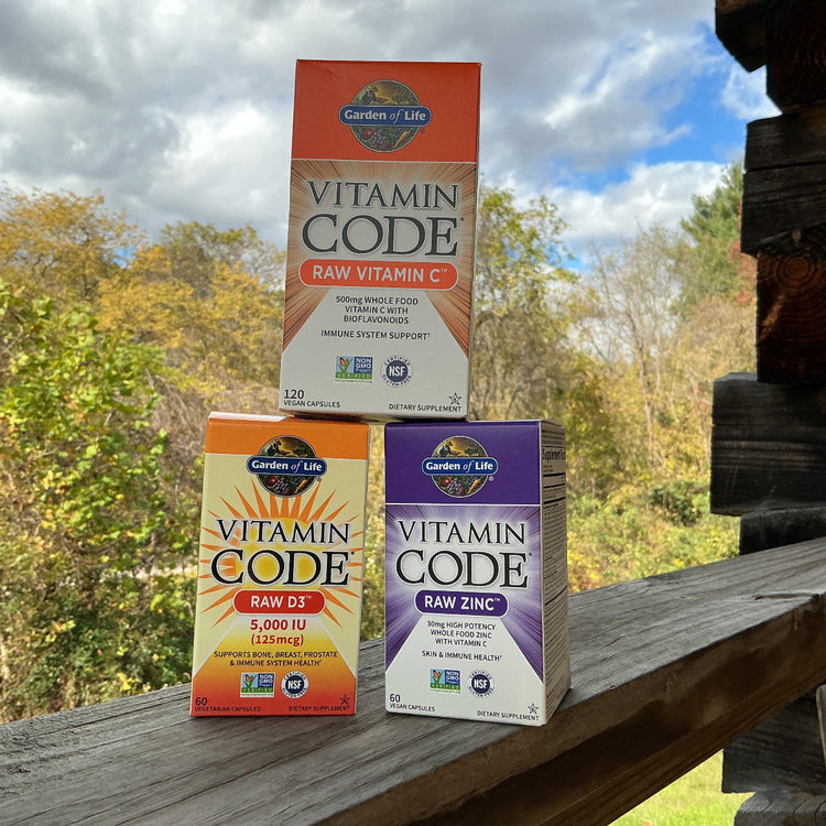 Three boxes of Garden of Life Vitamin Code supplements on a wooden surface with a natural background.