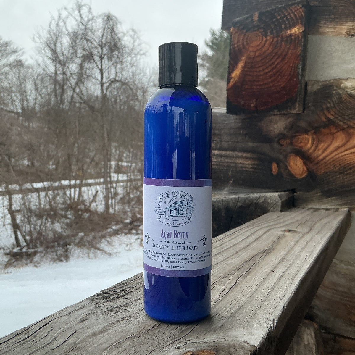 Blue bottle of body lotion on a wooden surface with a snowy landscape in the background