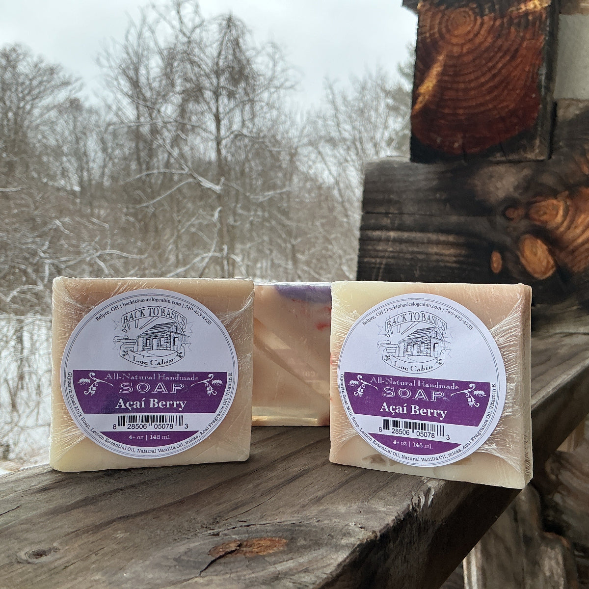 Two bars of soap with purple labels on a wooden surface outdoors.