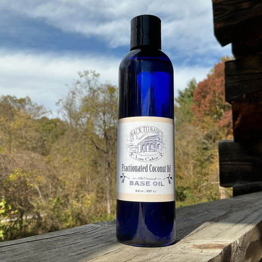 Bottle of fractionated coconut oil on a wooden surface with trees in the background