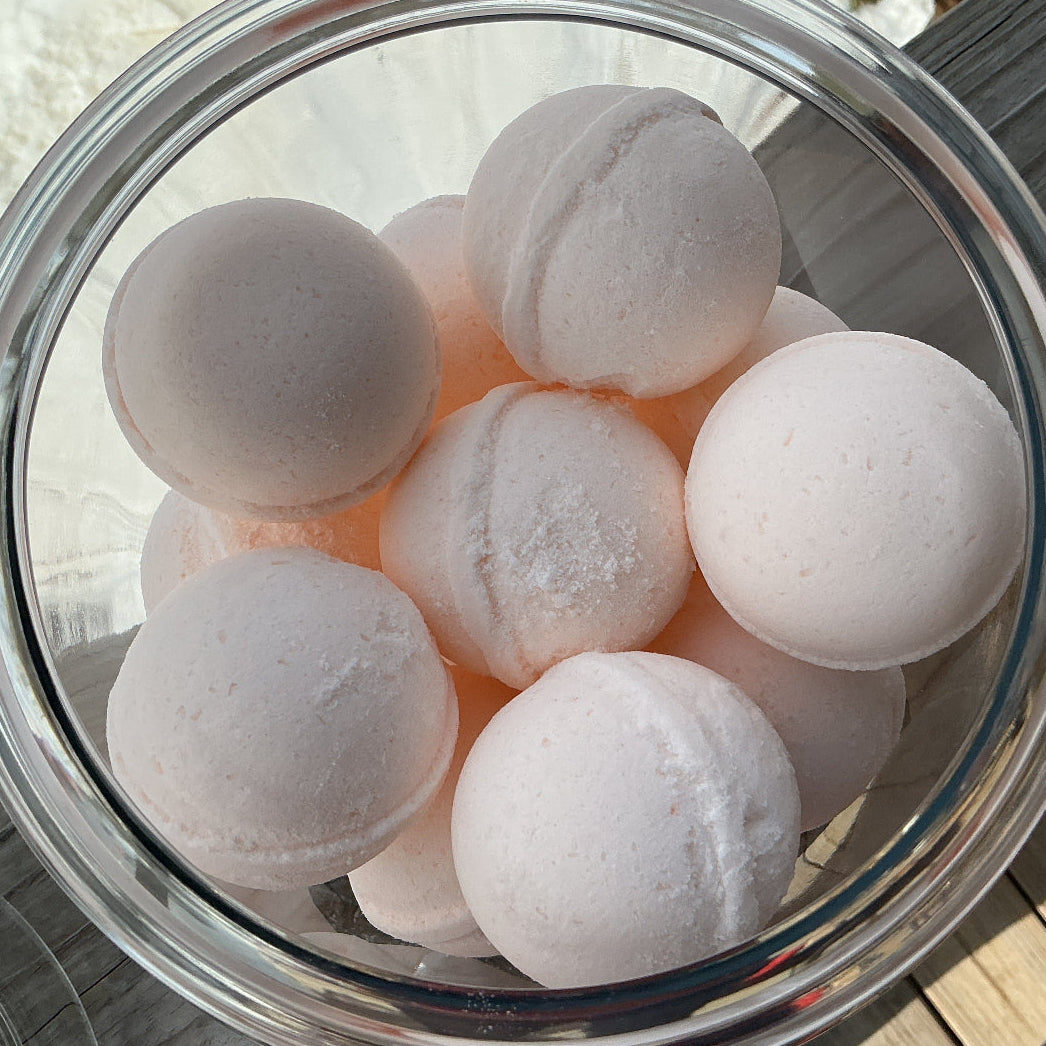 Clear glass bowl filled with white bath bombs on a wooden surface.
