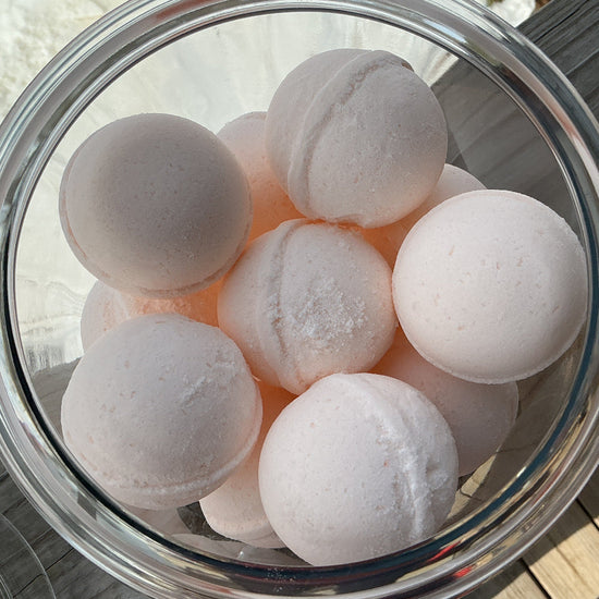 Clear glass bowl filled with white bath bombs on a wooden surface.