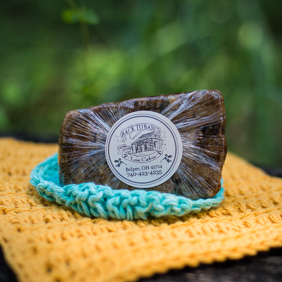 Bar of soap on a teal soap dish with a blurred green background