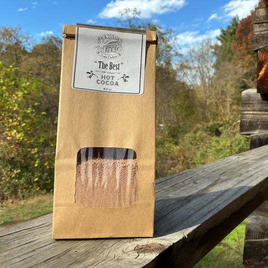 Kraft paper packaging of 'The Best' cocoa on a wooden surface with a natural background