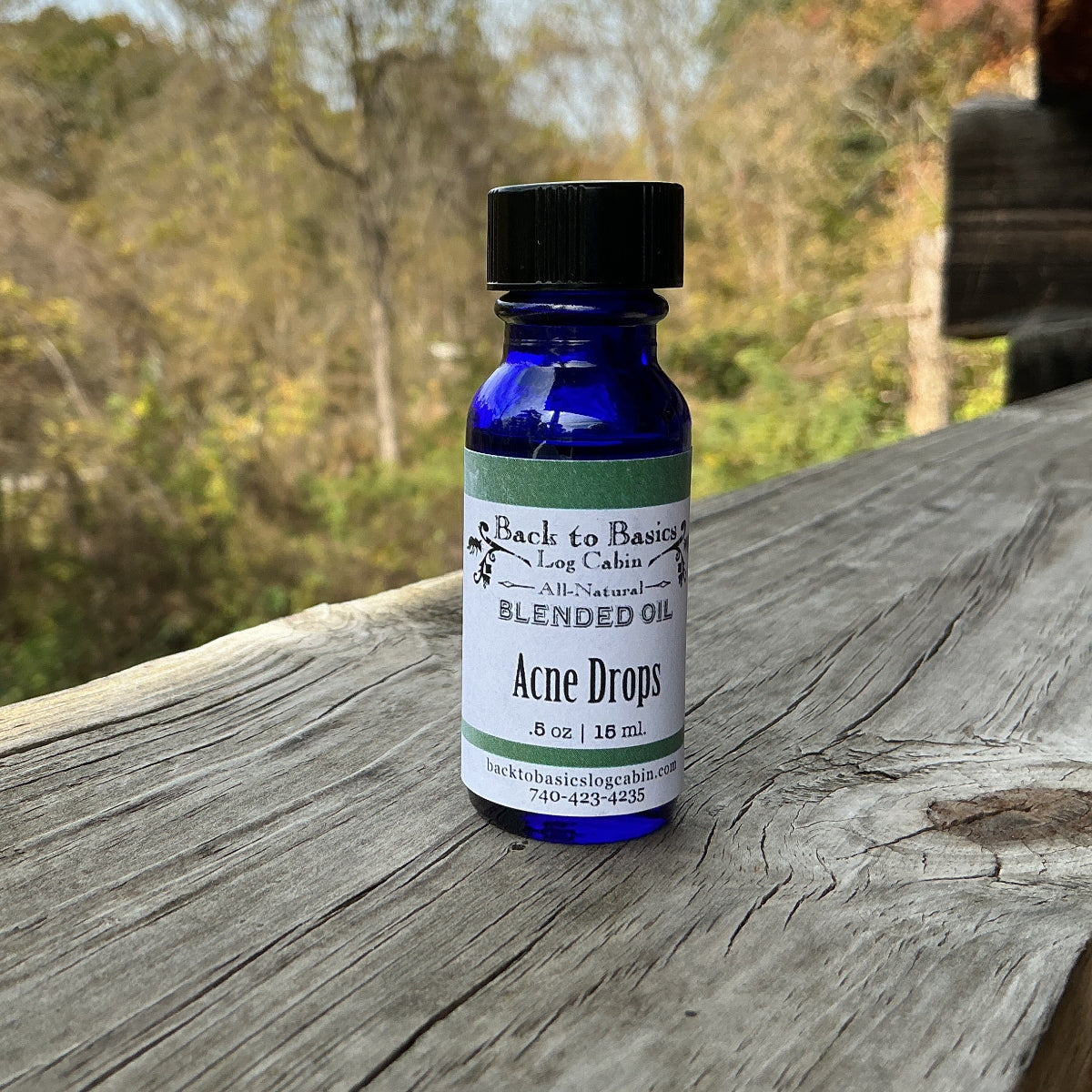 Bottle of 'Acne Drops' blended oil on a wooden surface with a natural background