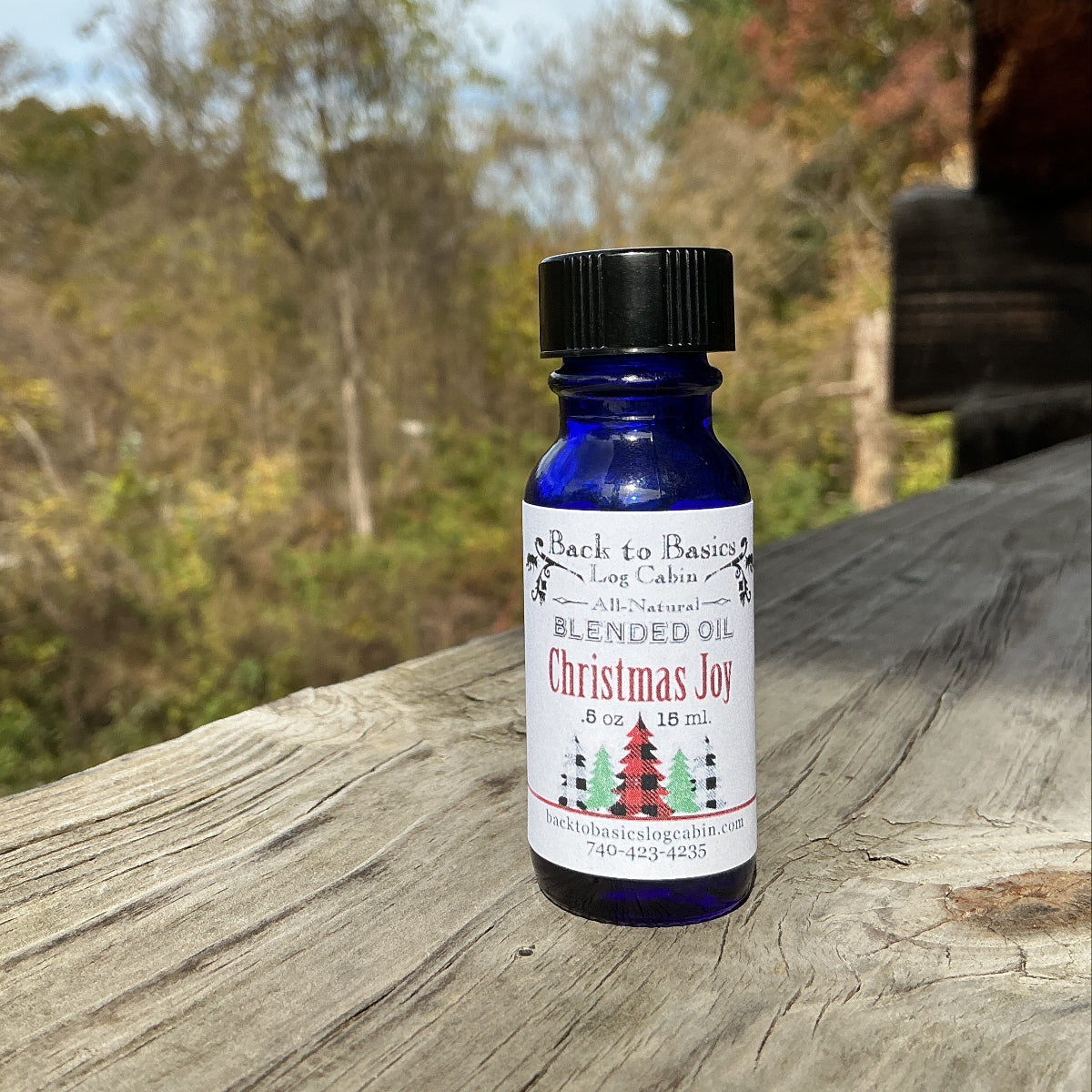 Bottle of 'Christmas Joy' essential oil blend on a wooden surface with a natural background
