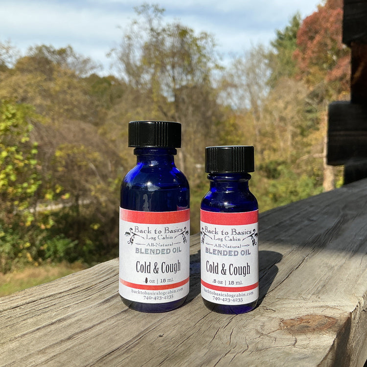 Two bottles of 'Back to Basics' cold and cough medicine on a wooden surface with a natural background.