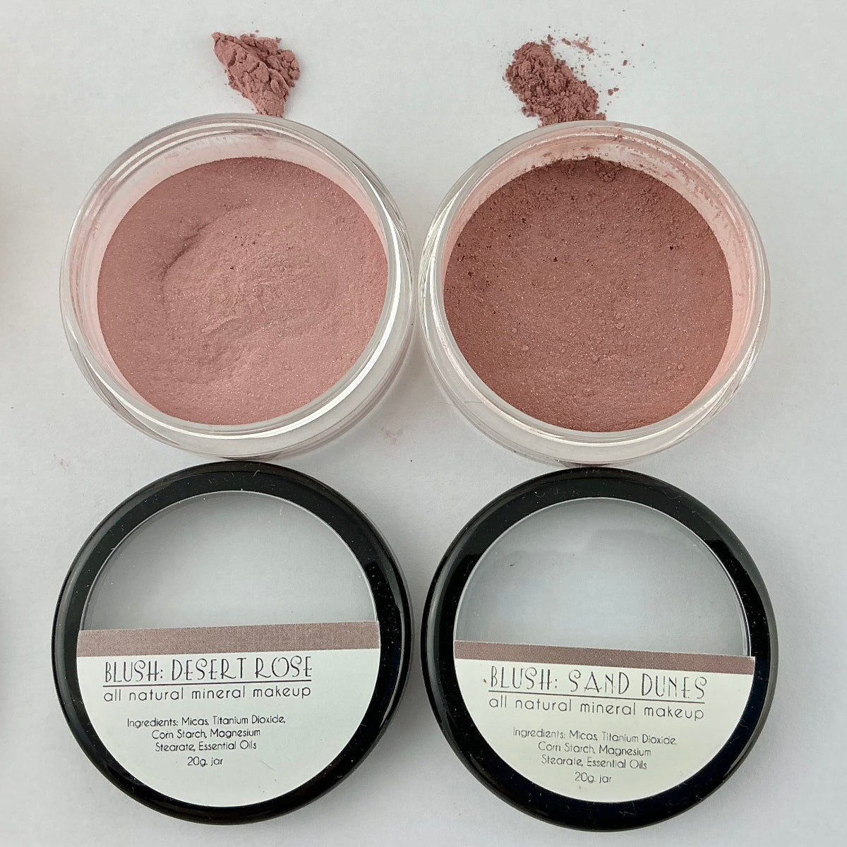 Two open jars of blush makeup with visible blush powder on a white background