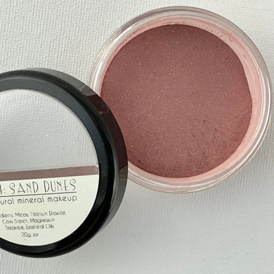 Open container of blush with a mirror on a light gray background