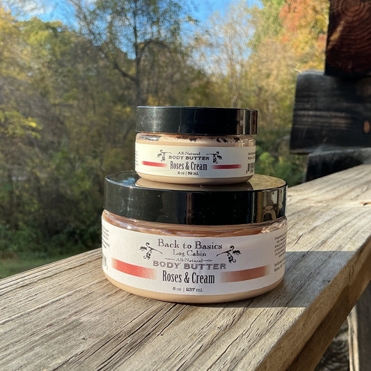 Three jars of body butter stacked on a wooden surface with a natural outdoor background